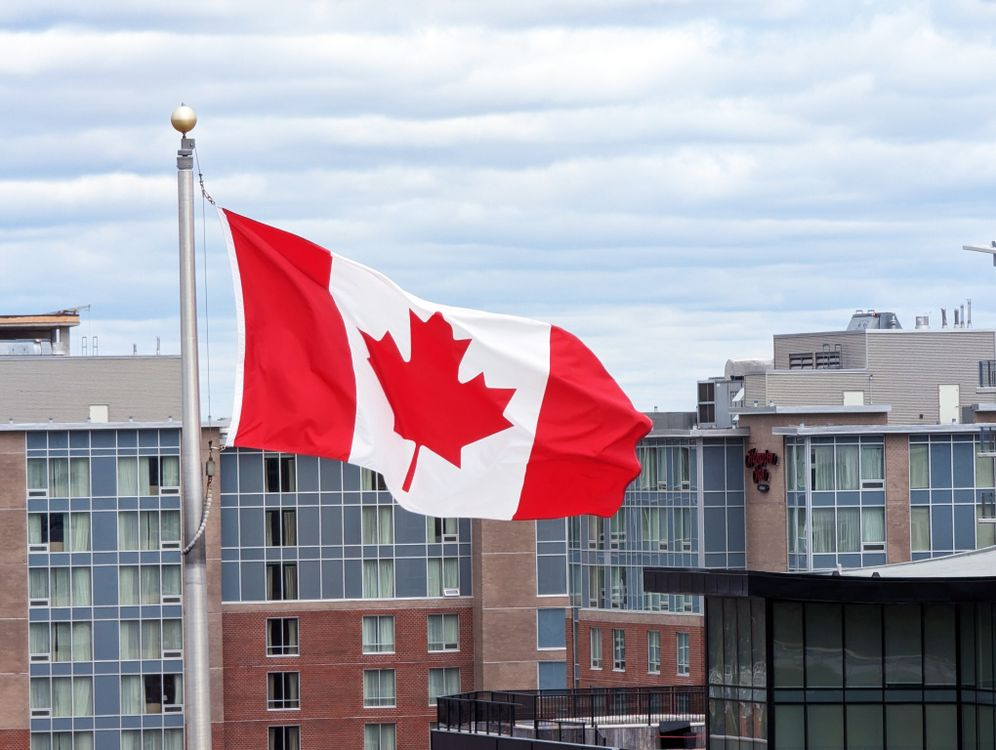 Canadian flag flying in front of a modern city building
